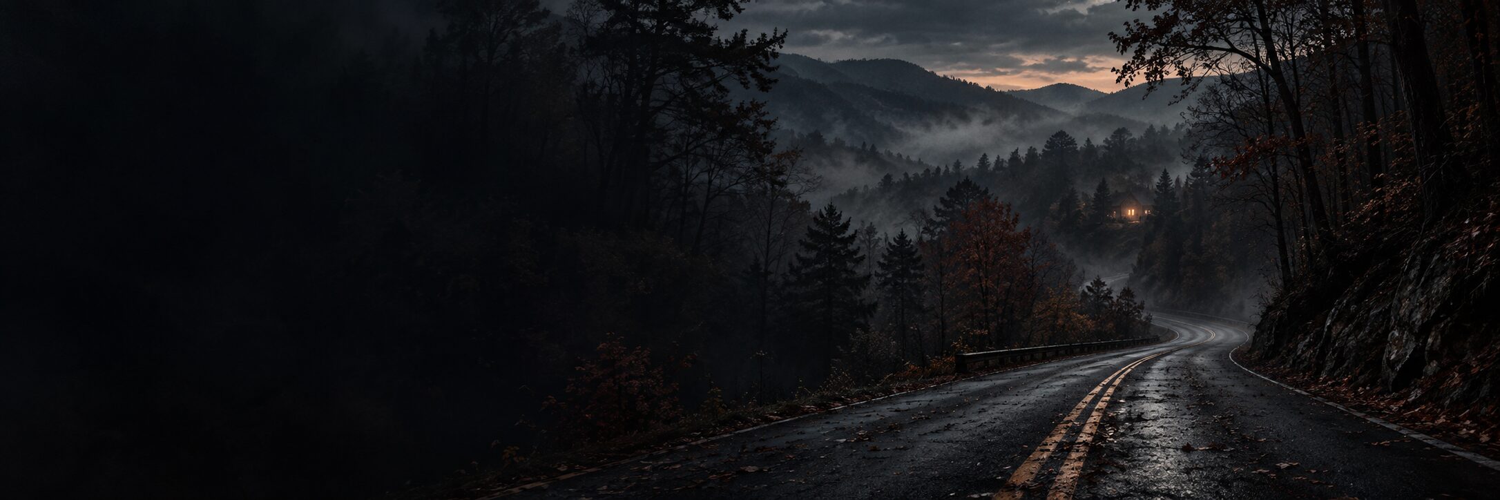 A rain-darkened road winding through foggy Appalachian woods at dusk